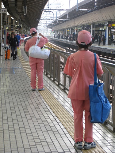 A cleaning team awaits an incoming JR Shinkansen train.